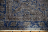 A close-up view of the distressed low pile showing mostly even wear to the knot heads in charcoal and cobalt blue.