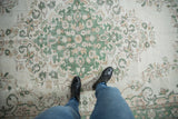 Vintage Oushak rug close-up of low pile, ivory foundation, and green floral pattern.