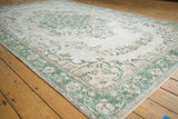Distressed vintage Oushak rug detail showing faded green and ivory floral vinery with even wear.