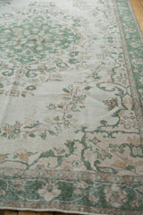Distressed vintage Oushak rug detail showing green vinery, ivory field, and wear to foundation.