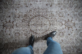 Distressed Oushak carpet surface showing faded silver and dark charcoal floral motifs.
