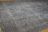 Distressed Oushak carpet corner, showing silver pile wear and dark chocolate floral patterns.