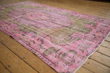 Distressed vintage Oushak carpet in pink, mauve, and olive green, with worn pile.