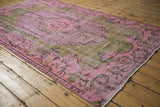 Distressed overdyed Oushak rug corner, pink and olive palette with knot head wear.