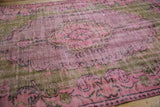 Distressed pink and olive green vintage Oushak carpet pile, showing worn texture.