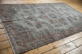 Distressed Oushak rug corner, muted floral patterns, worn knot heads, and fringe detail.