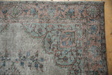 Worn silver pile of distressed vintage Oushak rug, showing foundation and muted florals.
