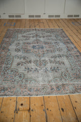 Distressed vintage Oushak rug edge with faded texture and intact white fringe.