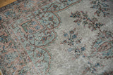 Faded pile and floral sprays in silver, blue, and dusty sandalwood on this distressed Oushak carpet.