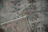 Distressed vintage Oushak rug close-up showing foundation, fringe, and worn floral pile.