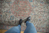 Distressed Oushak rug showing worn floral vinery in dusty terracotta and sky blue.