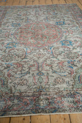 Distressed Oushak rug with terracotta, blue, green vinery, showing mostly even pile wear.