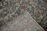 Distressed vintage Oushak rug's folded corner, revealing worn pile, woven foundation, and soft colors.
