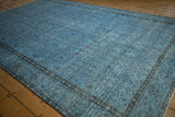 Distressed Oushak carpet with worn pale blue pile revealing subtle dark floral motifs.