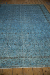 Distressed vintage Oushak carpet texture, pale denim blue pile, visible foundation, and floral vinery.