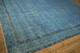 Close-up of the vintage Oushak rug's side selvage, showing distressed blue pile and faded motifs.