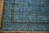 Distressed denim blue Oushak rug corner, showing faded pattern, exposed knot heads, and fringe.