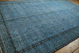 Distressed Oushak carpet corner, faded denim blue with dark floral vinery and visible wear.