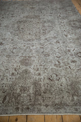 Close-up of distressed Oushak carpet pile, silver and brown Rococo vinery, faint foundation, and selvage.