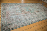 Distressed pile of a vintage Oushak carpet, showing wear to foundation, with pale turquoise and blush florals.