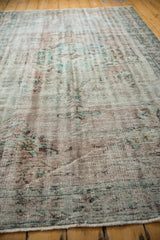 Close-up of time-softened vintage Oushak pile, revealing distressed pale turquoise and mauve motifs.