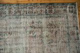 Textured distressed pile with wear to knot heads, revealing faded pale turquoise motifs.