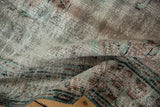 Textured distressed pile of a vintage Oushak rug revealing faded turquoise and brown patterns.