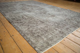Distressed Oushak rug corner, featuring faded silver and chocolate brown motifs.