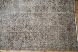 Oxidized silver and chocolate distressed Oushak rug with visible border and side selvage.