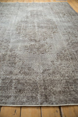 Distressed Oushak pile texture in oxidized silver and chocolate brown, revealing faded patterns.