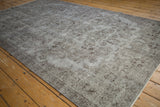Textured pile of a distressed Oushak rug, showing faded silver tones and chocolate floral patterns.