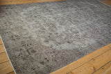 Distressed vintage Oushak rug corner, silver and chocolate floral patterns, showing foundation wear and selvage.