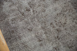 Distressed Oushak rug close-up showing oxidized silver floral pattern, mostly even wear, and selvage.