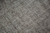 Distressed Oushak rug's textured pile with subtle scrolling vinery in silver and charcoal tones.