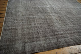 Distressed Oushak carpet close-up, revealing textural variation with soft silver and charcoal tones.
