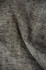 Textured pile detail of distressed Oushak rug in oxidized silver and charcoal tones.