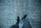Vintage distressed Oushak carpet with worn dusty blue pile, faint floral patterns, and visible foundation.