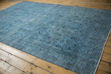 Distressed Oushak rug's dusty blue field with faded floral motifs and time-softened tones.