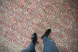 Distressed Oushak carpet showing worn brick red Herati motifs and visible ivory foundation.