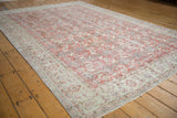 Distressed Oushak carpet, showing faded brick red Herati field, floral border, and mostly even wear.