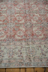 Faded brick red and ivory Oushak carpet texture with visible knot heads and foundation.