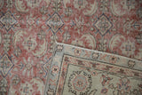 Distressed vintage Oushak: faded red field, visible foundation, folded to reveal ivory, red, blue border.