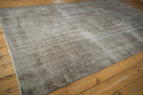 Corner view of distressed vintage Oushak carpet, highlighting silver pile texture and faded pattern.