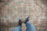 A person's view standing on a distressed vintage Oushak, showing the low-pile texture.