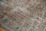 Worn corner of a distressed Oushak carpet showing the checkered seed design and floral border.