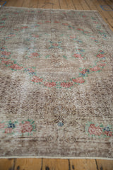 Low angle view of the distressed Oushak rug's pile showing time-softened rose and mint floral motifs.