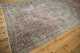 Distressed Oushak carpet from an angle, with a silvery overdyed pile and faded rose bouquet border.
