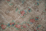Close-up of the distressed Oushak pile, revealing knot heads and dusty brick red rose motifs.