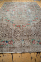 Angled view of the checkered seed design and rose motifs on a distressed overdyed Oushak rug.