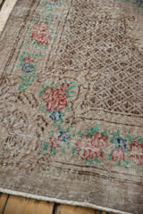Checkered seed design and rose bouquet border on the corner of a distressed Oushak carpet.